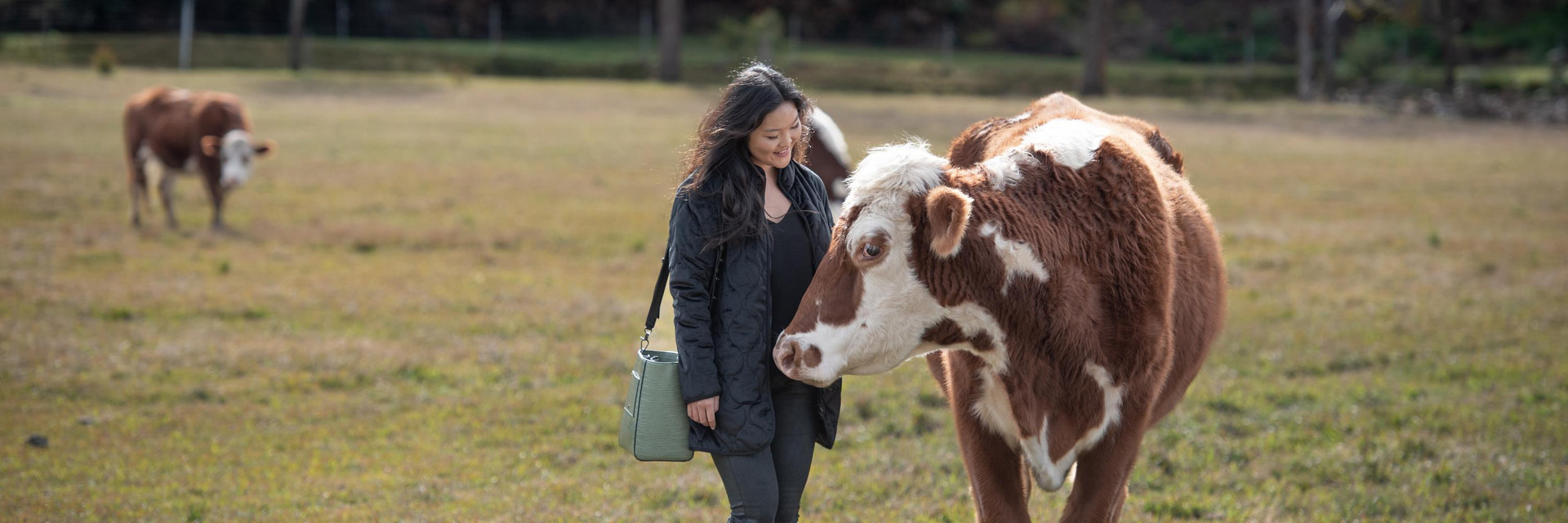 Woman wearing ethical fashion standing next to a cow