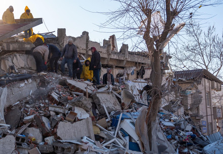 People standing on the rubble of destroyed buildings in Antakya, southern Türkiye