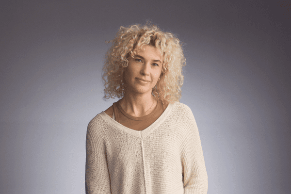 Artist and comedian Lucy Blehar sitting in front of gray background